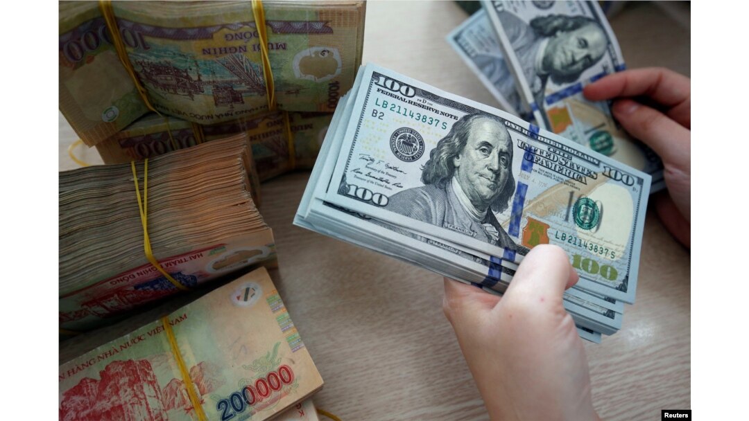 An employee counts U.S. banknotes among Vietnamese banknotes at a branch of Vietnam Prosperity Joint Stock Commercial Bank (VPBank) in Hanoi, Vietnam November 15, 2017. (REUTERS/Kham)