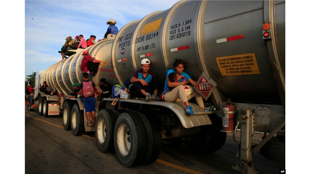 A woman holding her baby hitches a ride on the fender of a tanker in Niltepec, Mexico, Oct. 30, 2018.