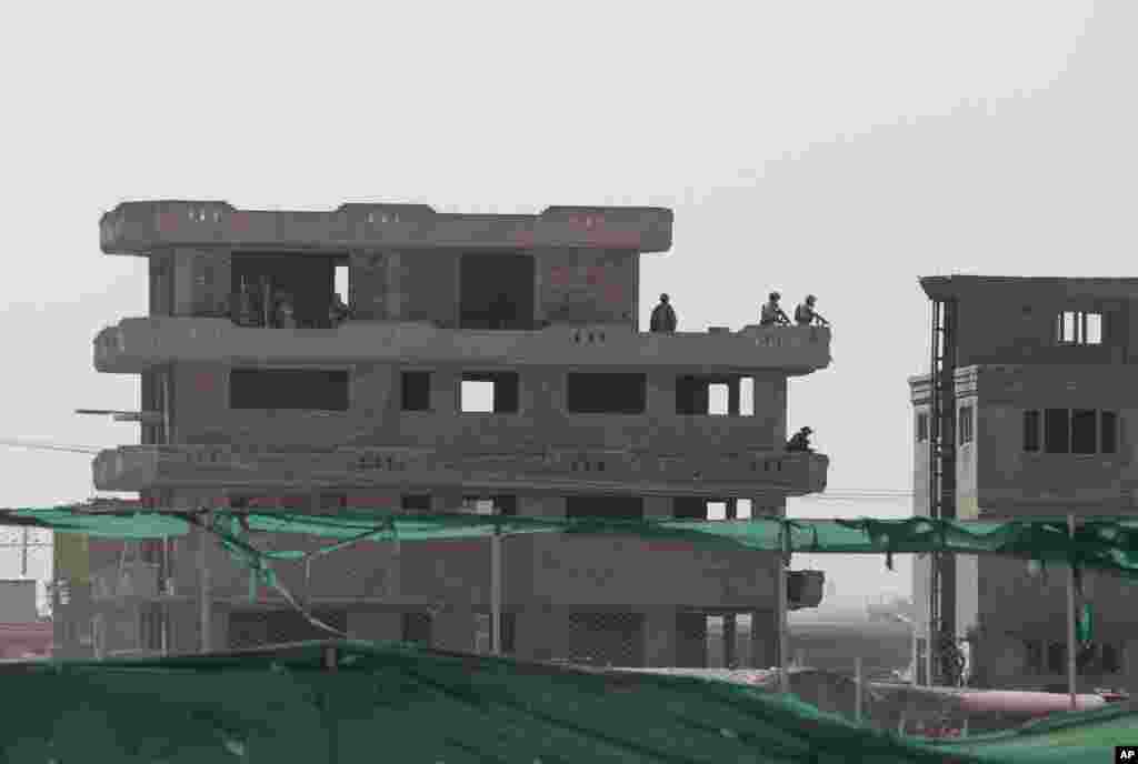 Afghan soldiers patrol a building after a Taliban attack near Kabul airport, June, 10, 2013.