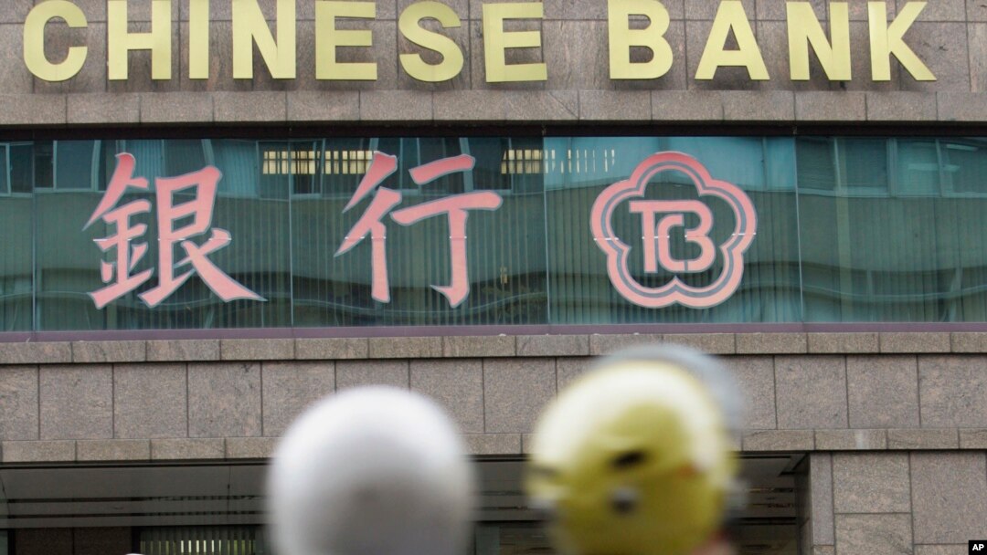 FILE - In this file photo from Jan. 16, 2007, motorcyclists pass by a branch of The Chinese Bank in Taipei, Taiwan. 