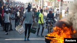 Manifestantes haitianos se congregan detrás de una barricada en llamas durante las protestas contra el presidente Jovenel Moise, en Puerto Príncipe, el 7 de febrero de 2021.