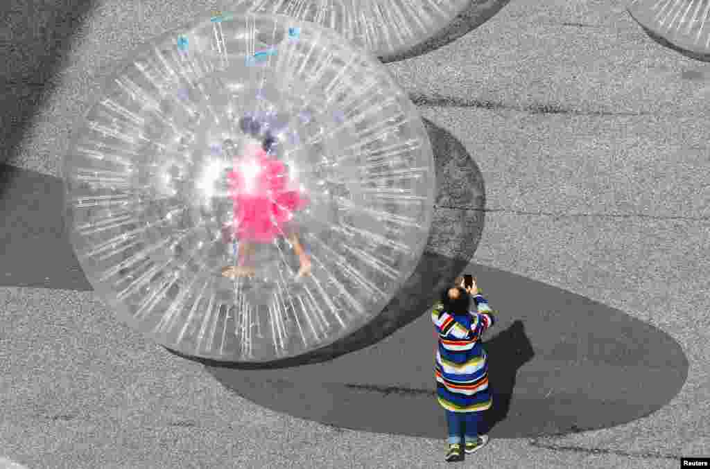 An artist is seen in a transparent plastic ball during the performance "Tears" by Monster Chetwynd in front of the venue of the Art Basel art fair at the Messeplatz square in Basel, Switzerland.