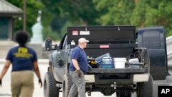 Authorities investigate a pickup truck parked on the sidewalk in front of the Library of Congress' Thomas Jefferson Building, in Washington, Aug. 19, 2021. A man who claimed to have a bomb surrendered to law enforcement after an hourslong standoff.