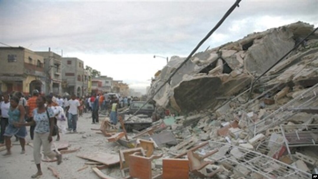 Haitians walk past damaged buildings in Port-au-Prince, 12 Jan 2010