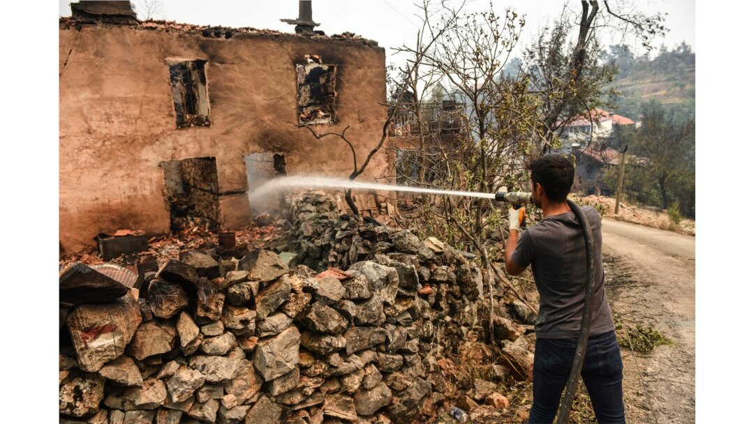 A man extinguishes a fire in his house in Semir village, near Manavgat, Antalya, Turkey, Aug. 3, 2021.