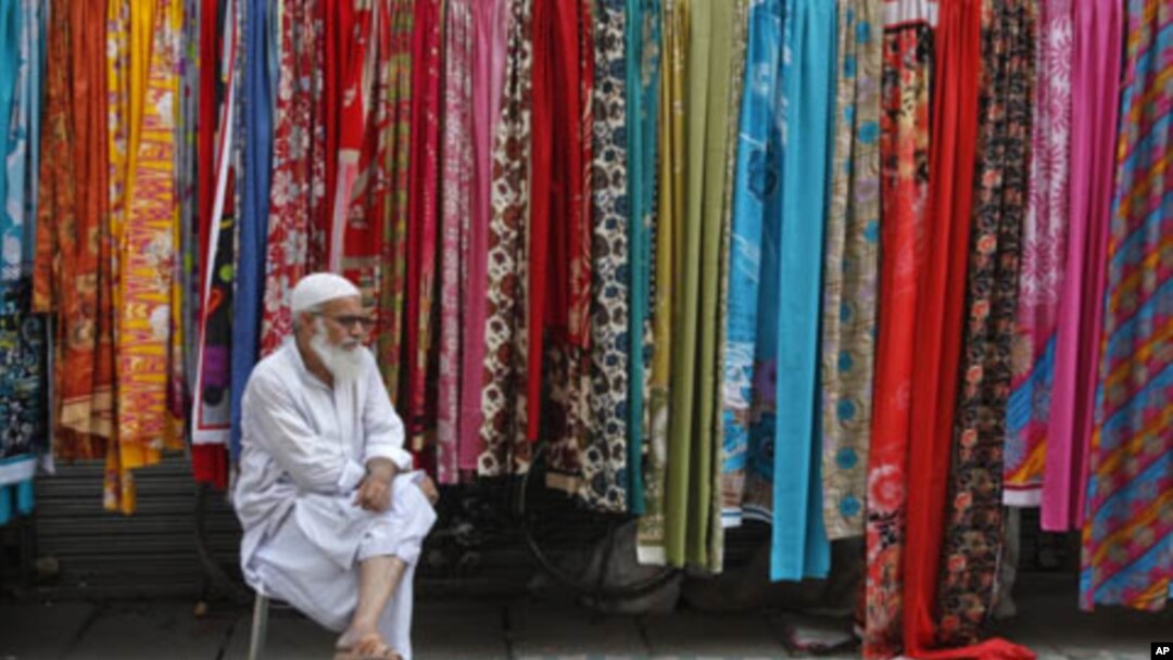 A man selling fabric waits for customers at a roadside stall in Lahore, Pakistan, September 25, 2011.