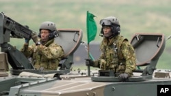 資料照片：日本陸上自衛隊員乘坐自行榴彈砲車在御殿場市的東富士演習場參加實彈演習。(2021年5月22日)
