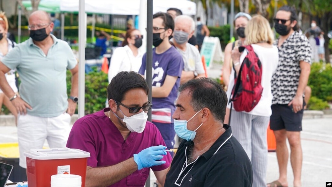 FILE - Carlos Anacleto closes his eyes as he receives the Pfizer COVID-19 vaccine from nurse Jorge Tase, as others wait their turn, Aug. 4, 2021, in Miami Beach, Fla. 