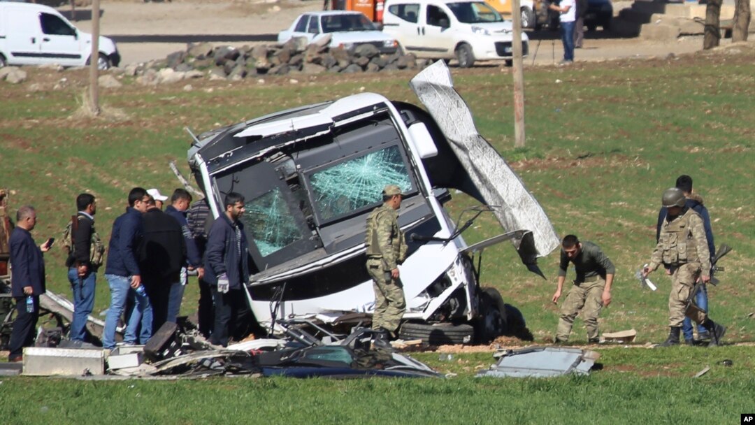 FILE - Members of Turkish forces gather around a bus that was destroyed in an explosion on the road linking the cities of Diyarbakir and Bingol, in southeastern Turkey, Feb. 18, 2016. Turkish police arrested 10 suspected Islamic State members in raids Thursday in the area.