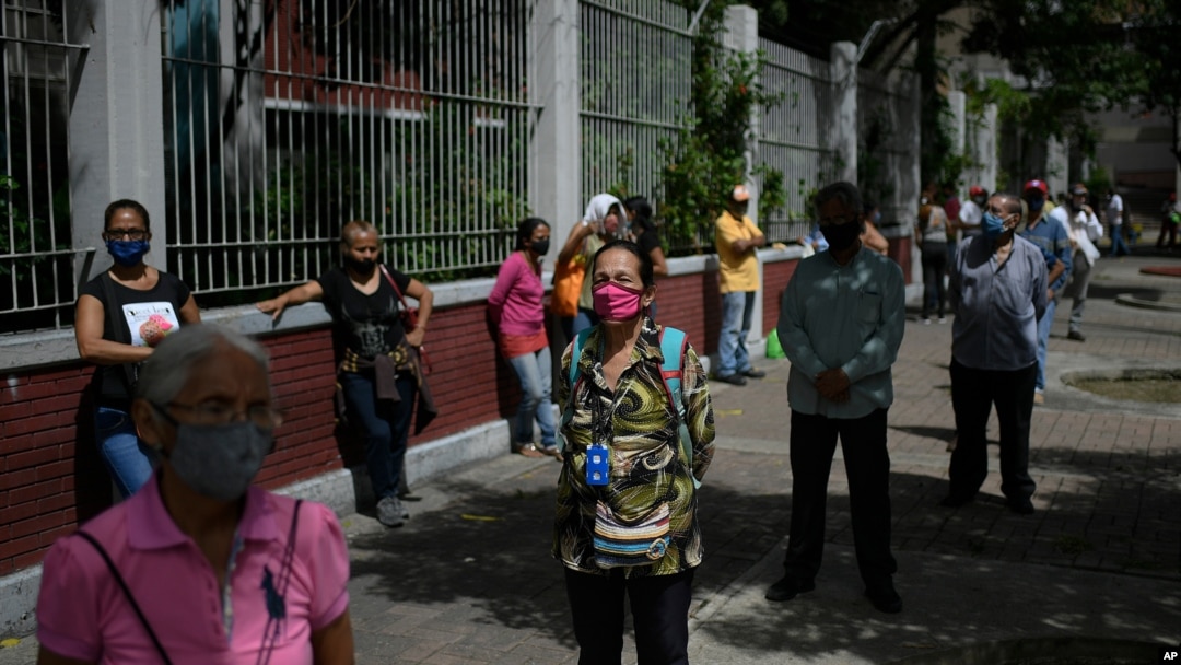 Personas con mascarillas esperan para votar durante un simulacro electoral en una escuela secundaria en Caracas, Venezuela. Octubre 25, 2020.