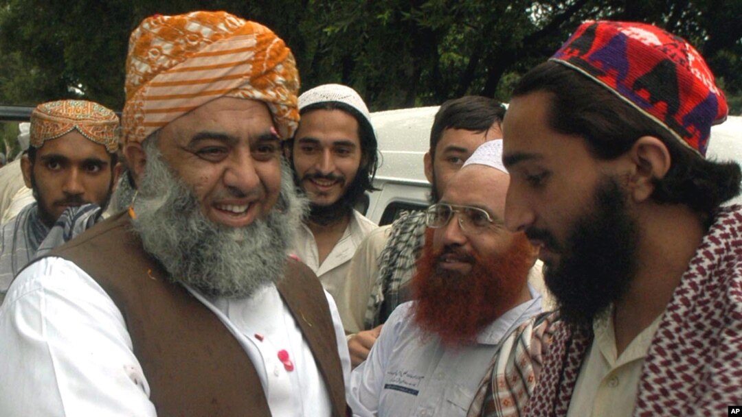 FILE - Maulana Fazl-ur-Rahman, left, leader of Pakistan's Jamiat Ulema-e-Islam party, is received by followers as he arrives in Pakistan at a border post near Lahore after a trip to India, July 24, 2003.