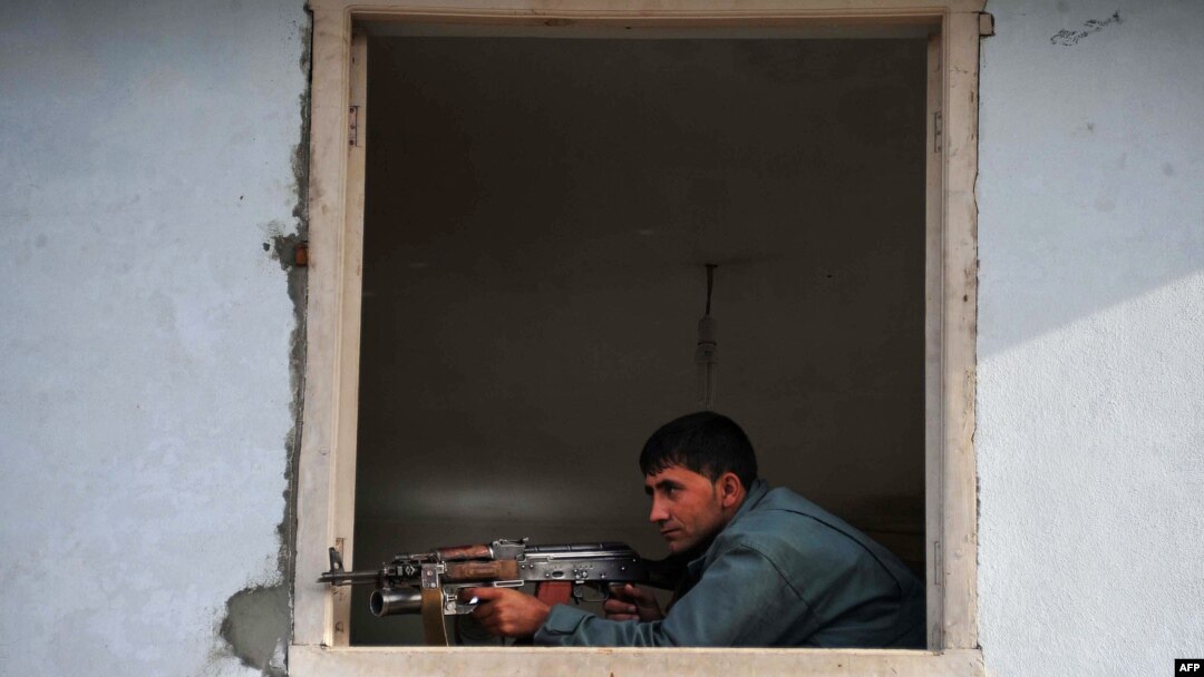 An Afghan policeman takes position at the site of a suicide attack in Jalalabad, March 26, 2012.