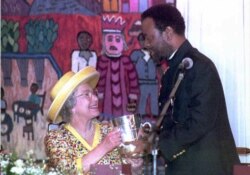 FILE - British Queen Elizabeth II looks up to Zulu King Zwelithini as he presents her a replica of a cup given to King Cetshwayo by Queen Victoria in 1882, here at a ceremonious luncheon in Durban, March 25, 1995.