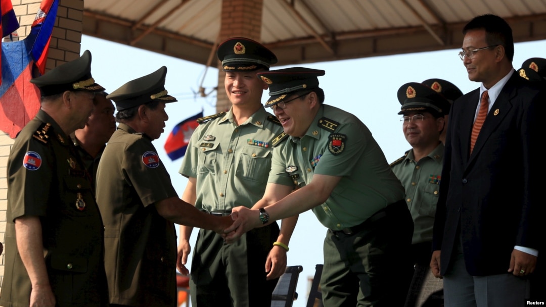 FILE - Cambodian Defense Minister Tea Banh, second left, shakes hands with a Chinese army adviser during a graduation ceremony at the Army Institute in Kampong Speu province, March 12, 2015. 