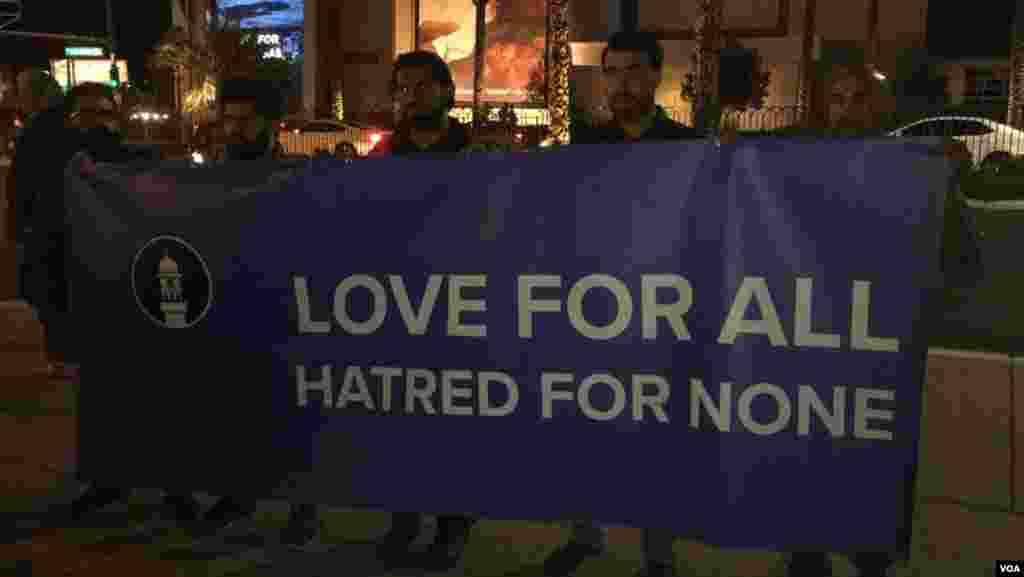 Men hold banner promoting unity and love at candlelight vigil for victims of Las Vegas mass shooting, Oct. 2, 2017. (Photo: C. Mendoza / VOA)