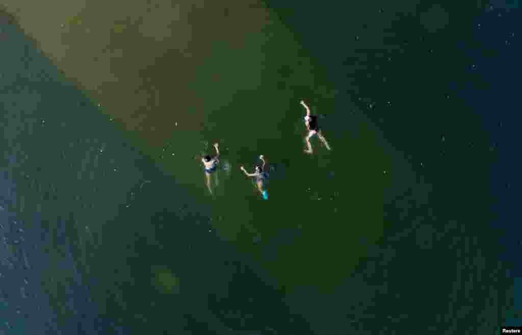 An aerial view shows youths swimming in the Yenisei River on a hot summer day, with the air temperature at about 30 degrees Celsius (86 degrees Fahrenheit), outside Krasnoyarsk, Russia.