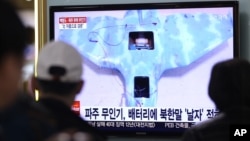 People watch a TV news program showing an unmanned drone, at the Seoul Railway Station, South Korea, April 2, 2014.