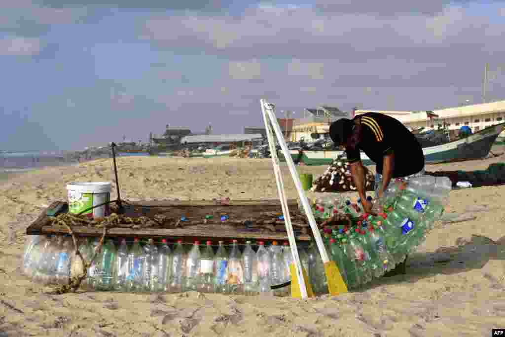 Palestinian fisherman Mouad Abu Zeid repairs his boat that he made of 700 Plastic empty bottles on a beach in Rafah in the southern Gaza Strip on August 14, 2018.