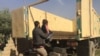 A father loads his child into an army truck to go to an internally displaced persons' camp in the Mosul suburbs, Iraq, Nov. 12, 2016. (H.Murdock/VOA)