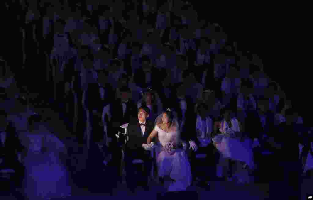 A couple watches a screen during a mass wedding ceremony at the Cheong Shim Peace World Center in Gapyeong, South Korea, Monday, Aug. 27, 2018.