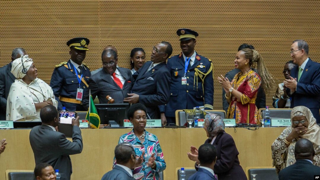 African Union chairman Chadian President Idriss Deby, fourth left, receives the instruments of office from his predecessor Zimbabwean President, Robert Mugabe, as AU Commission Chairperson Nkosazana Dlamini Zuma, left, African Union chairman Chadian President Idriss Deby, fourth left, receives the instruments of office from his predecessor Zimbabwean President, Robert Mugabe, third left in red tie, as African Union Commission Chairperson Nkosazana Dlamini Zuma, left, and UN Secretary General , Ban Ki-moon, right, watches, in Addis Ababa.