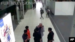 In this image made from airport closed circuit television video and provided by Fuji Television, Kim Jong Nam, exiled half-brother of North Korea's leader Kim Jong Un, gestures towards his face while talking to airport security and officials at Kuala Lumpur international airport.