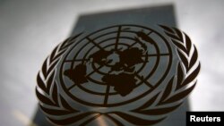 FILE - The United Nations headquarters building is pictured though a window with the UN logo in the foreground.