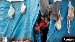 FILE - Displaced Syrian children look out from their tents at Kelbit refugee camp, near the Syrian-Turkish border, in Idlib province, Syria, Jan. 17, 2018. 