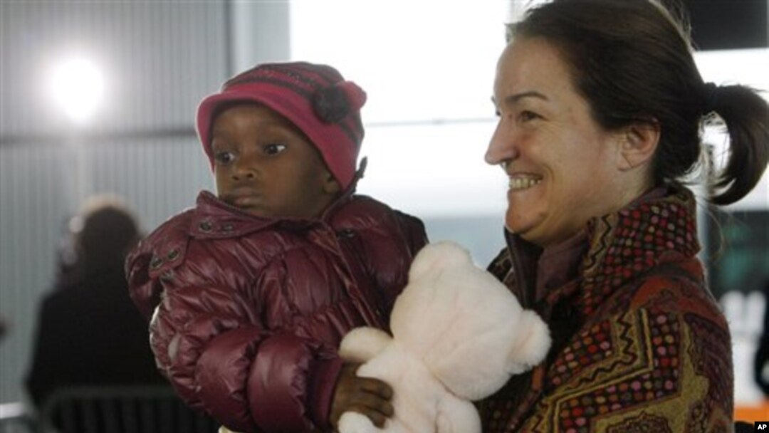 A French adoptive parent carries an orphan from Haiti at Roissy airport, outside of Paris, 22 Dec 2010