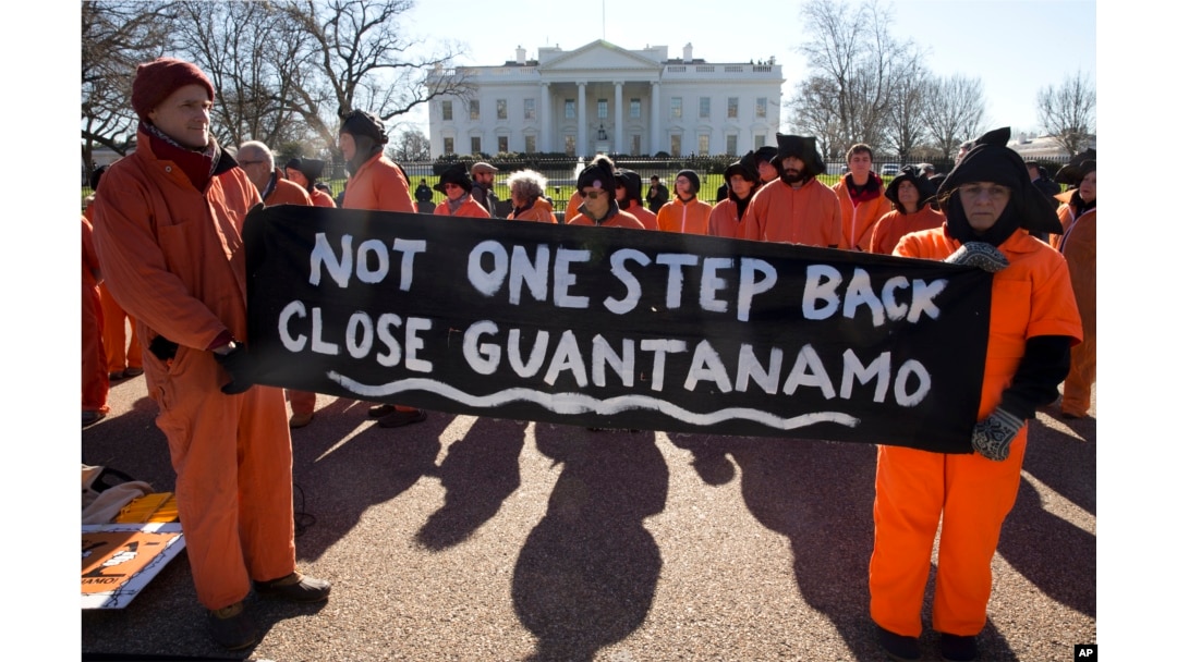 Protesters depicting Guantanamo Bay detainees hold signs calling for closing the Guantanamo Bay detention center in Cuba, at a rally at the White House in Washington, Jan. 11, 2016.