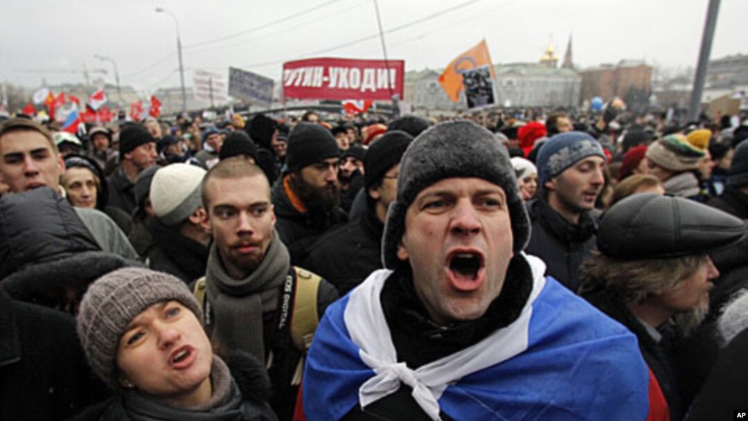Masu zanga zangar a dandalin Bolotnaya a birnin Moscow. A bayansu kuma alame ce dake kira ga Prime Minista Putin yayi murabus.