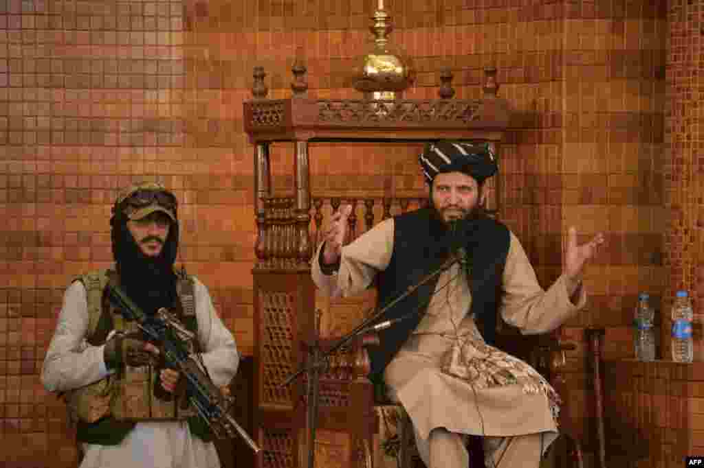 An Imam speaks next to an armed Taliban fighter during Friday prayers at the Abdul Rahman Mosque in Kabul, following the Taliban's stunning takeover of Afghanistan.