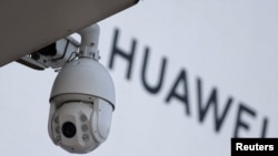 资料照：在北京一家商场外的华为标志旁安装了一个监控摄像头。（2019年1月29日）