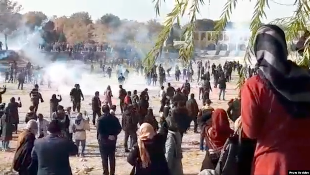 Iranian security forces appear to fire tear gas at anti-government protesters on the dry bed of the Zayandehrud River in Isfahan in this screen grab of a video posted to social media on Nov. 26, 2021. Isfahan's centuries-old Khajoo bridge can be seen at the upper right.