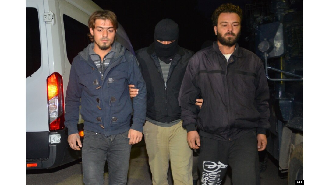 FILE - A masked Turkish special force police officer detains two men during a house raid to arrest suspected members of the Islamic State group, in Adana, on Nov. 10, 2017.