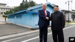时任美国总统特朗普在韩国非军事区的板门店停战村和朝鲜领导人金正恩握手。(美联社：2019年6月30日)