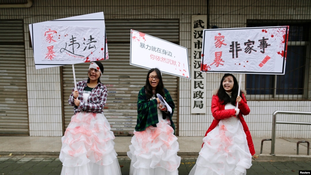 FILE - University students dressed as battered wives hold banners in front of an office of China's Civil Affairs department, where local people register for marriage, in protest of domestic violence, during the International Day for the Elimination of Violence against Women, in Hubei province, Nov. 25, 2012. 