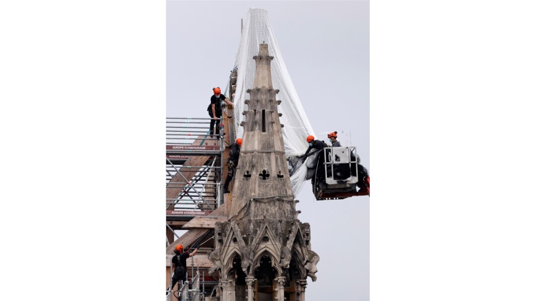 Workers prepare to remove damaged scaffolding elements from the remains of the damaged roof of Notre Dame Cathedral in Paris, June 8, 2020