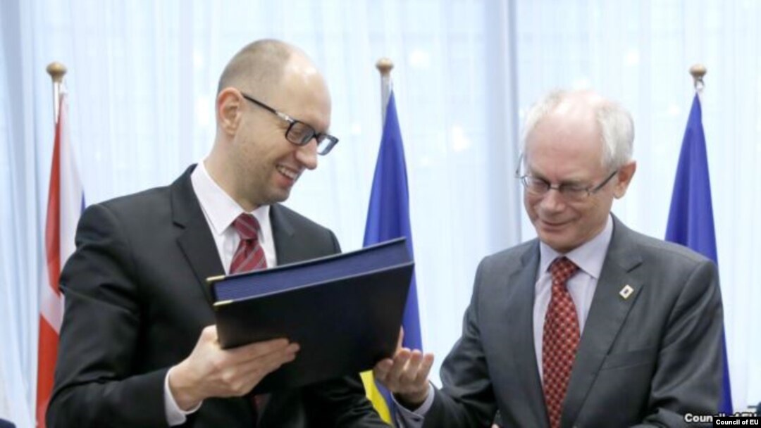 Ukrainian Prime Minister Arseniy Yatsenyuk (left) and European Council President Herman Van Rompuy exchange documents at the signing ceremony in Brussels on March 21.