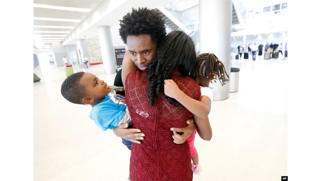 Olympic silver medalist Feyisa Lilesa, rear, of Ethiopia, hugs his wife Iftu Mulia, his daughter Soko, right, 5, and son Sora, left, 3, while picking up his family at Miami International Airport, Feb. 14, 2017.