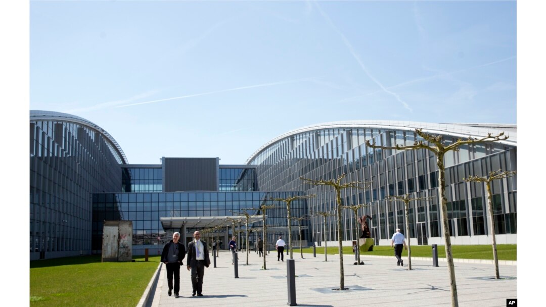 People walk outside the entrance of the new NATO headquarters in Brussels on April 19, 2018. NATO ministers will hold their last meeting in the old headquarters on April 27, 2018 before moving permanently to a new building across the street.