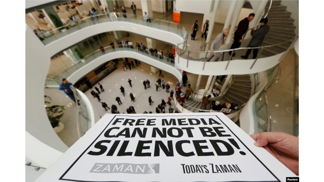 FILE – A journalist holds a banner at the headquarters of Zaman daily newspaper in Istanbul on Dec. 14, 2014, after Turkish police raided a television station and newspaper.