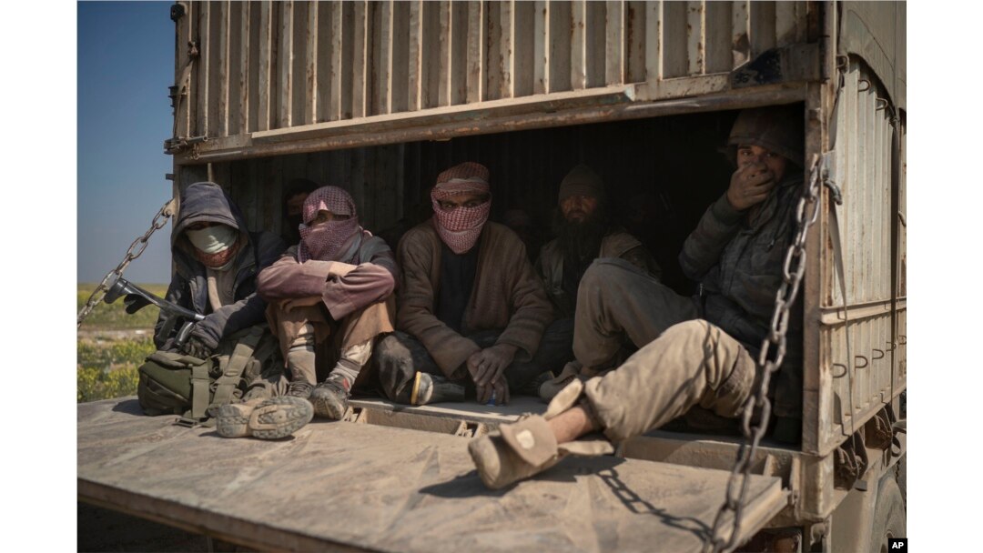 Men ride in the back of a truck that is part of a convoy evacuating hundreds out of the last territory held by Islamic State militants in Baghuz, eastern Syria, Feb. 20, 2019.