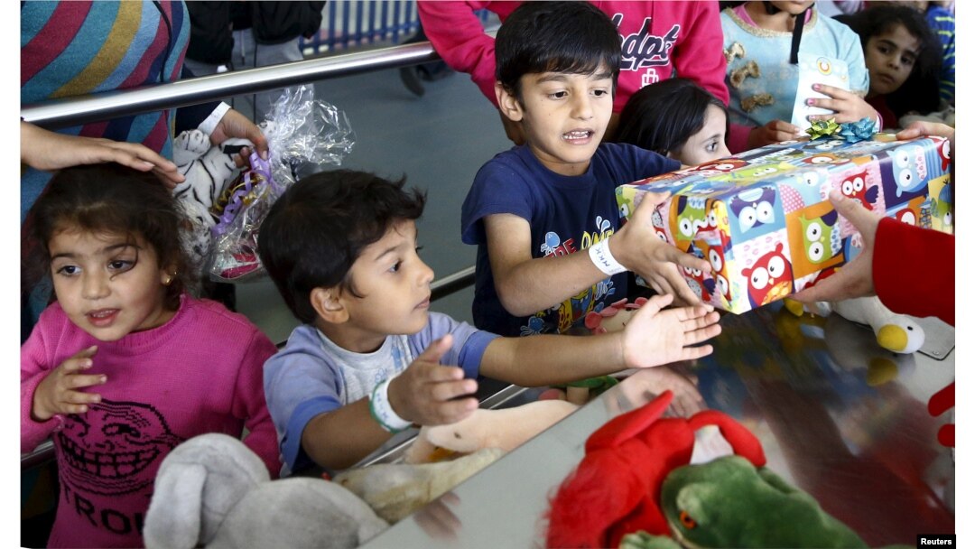 FILE - Migrant children reach out for gifts donated by the local community for the Bayram festivities at an improvised temporary shelter in a sports hall in Hanau, Germany, Sept. 24, 2015.