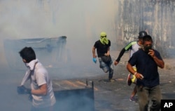 Demonstrators run away from a cloud of tear gas during clashes with the Bolivar National Guard in Urena, Venezuela, near the border with Colombia, Feb. 23, 2019.