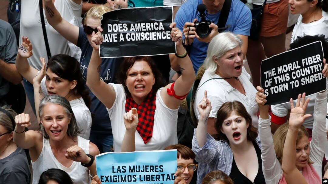Women hold signs as they protest the separation of immigrant families, June 28, 2018, inside the Hart Senate Office Building on Capitol Hill in Washington.