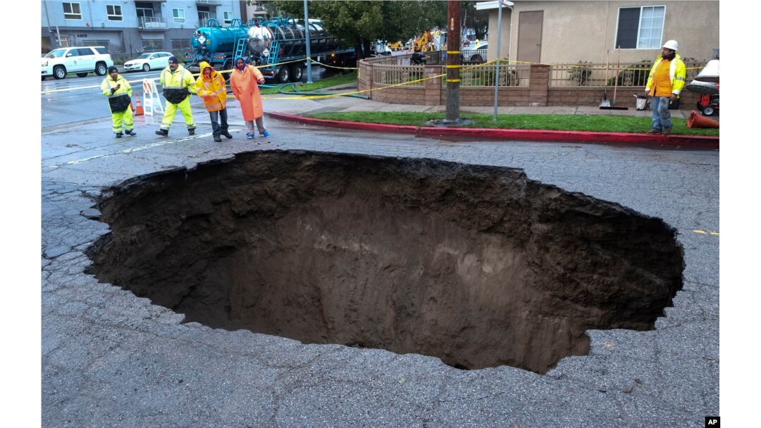 Inspectors examine a sinkhole in Studio City, north of Los Angeles, Feb. 18, 2017. Two vehicles fell into the 20-foot sinkhole on Friday night and firefighters had to rescue one woman who escaped her car but was found standing on her overturned vehicle.