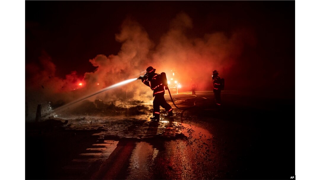 A firefighter sprays the smoldering remains of a vehicle on Interstate 5 as the Delta Fire burns in the Shasta-Trinity National Forest, Calif., on Sept. 5, 2018.