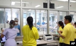 FILE - In this image made from video, released by Thailand Government Spokesman Bureau, family members watch the rescued boys through a window outside the recovery ward at the Chiang Rai hospital in Chiang Rai province, northern Thailand, July 11, 2018.