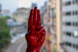 一名反军事政变抗议者用红漆染红的手举手行三指礼。（2021年4月6日）